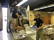 Two men load a van of supplies Two men load a van of supplies