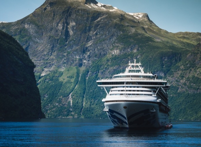 A small boat in a body of water with a mountain in the background Description automatically generated